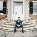 man in blue suit sitting on brown concrete stairs